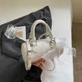 Detailed view of a white leather barrel bag with pearl charms and bow accessory - With Pendant / Off White