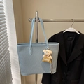 Détail du sac cabas bleu clair avec texture tissée, lanières en cuir et breloque ours - Bleu avec pendentif