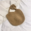 Macro detail of hand-woven crochet texture on a tan straw tote beach bag laid on fabric - Khaki