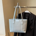 Light blue woven tote bag with leather straps for commuting, displayed on metal rack - Blue Without Charm