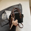 Detail einer schicken Kontrast-Handtasche mit Plüschbär-Anhänger und gestreiftem Schal - Schwarz Mit Anhänger
