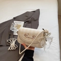 Détail d'un sac à bandoulière crème avec broderie de cœur et breloque noeud en perles - Blanc Cassé Avec Pendentif
