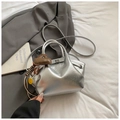 Detailed shot of silver dumpling bag with heart and smiley charms on white fabric - Silver with Charm