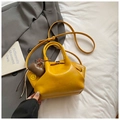 Detail of ginger yellow PU leather tote bag with smile charm on a grey suit jacket - Yellow with Pendant