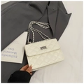 Detail of white quilted bag featuring a silver metal chain strap and cross twist lock closure - White