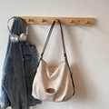 Minimalist beige tote bag with deep brown straps and brand logo on a wooden wall hook - Khaki