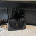 Gros plan du fourre-tout noir brillant avec pendentif doré et accessoires modernes - Noir