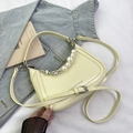 Detalle de bolso de hombro crema con perlas y cadenas metálicas con forma de corazón - Amarillo