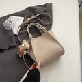 Detail of beige litchi texture handbag with bear charm and adjustable shoulder strap - Khaki With Pendant