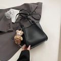 Detail view of black lychee leather handbag with metal feet and cute bear pendant - Black With Pendant