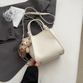 Detail of off-white pebble leather tote bag with a cute teddy bear charm and metal feet - Cream White with Pendant