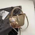 Close-up of beige lychee leather bucket bag with silver buckle and cute plush bear charm - Khaki With Pendant