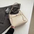 Detalle de bolso tote de cuero crema con cierre de broche metálico y colgante de cuero - Albaricoque