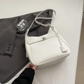 Detalle del bolso tote de cuero blanco con cierre giratorio plateado sobre traje gris - Blanco