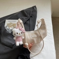 Detail of cream plaid dumpling bag with knotted handle and plush cat charm on bedding - Cream White with Pendant