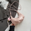 Close-up of pink semi-circle handbag featuring glossy leather texture and heart charm - Pink With Pendant