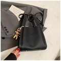 Close-up of black litchi grain leather bucket bag with silver studs and doll pendant - Black With Pendant