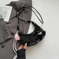 Detail der schwarzen Lackleder-Halbmondtasche mit rosa Barbie-Herz-Plüschanhänger - Schwarz Mit Anhänger