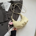 Detail einer cremegelben Halbmondtasche mit Falten-Design und rosa Herz-Anhänger am Gurt - Gelb mit Anhänger