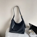 Detail der schwarzen Leder-Hobo-Tasche mit goldenen Beschlägen auf dem Schreibtisch - Schwarz