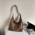 Detail of a large brown leather hobo bag next to a laptop in an office setting - Khaki