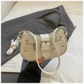 Detail of cream Y2K crescent bag featuring silver studs and adjustable shoulder straps - White