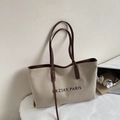 Détail d'un sac cabas en toile beige avec poignées en cuir marron et logo PARIS - Khaki avec Café