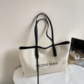 Close-up of minimalist canvas tote bag with black leather handles and laptop in the scene - White and Black