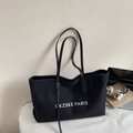 Detail view of large black canvas tote bag featuring CKZSKE PARIS text and leather handles - Black