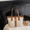 Detail of high-capacity beige and brown tote bag with metal logo and laptop in workspace - Off-white