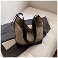 Detail of olive green slouchy tote bag with black leather base on a grey blazer - Grey and Black