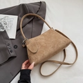 Minimalist brown suede baguette shoulder bag with slim strap shown in lifestyle setting - Khaki
