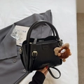 Elegant black lychee leather handbag with golden hardware and plush pendant detail - Black with Pendant