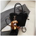 Detail of black lychee-grain tote bag with a brown plush bear and wavy top design - With Charm / Black