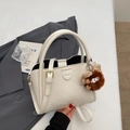 Chic beige lychee grain tote bag with top handles, crossbody strap, and plush charm - Beige With Charm