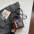 Gros plan détaillé d'un sac seau vintage marron foncé avec breloque et boucle dorée chic - Café (Avec Pendentif) / Marron avec Pendentif