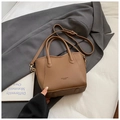 Braune Handtasche aus Leder mit Litschimuster, Henkeln und Logo auf grauem Anzug-Hintergrund - Ohne Anhänger / Braun