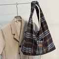 Brown and blue checkered wool tote bag with leather label hanging on a rack - Brown