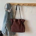 Dunkelbraune Wildleder-Beuteltasche mit Tunnelzug und goldener Kette in Wohnambiente - Kaffee Groß