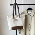 Detailed macro view of cream corduroy tote bag with brown leather handles and brand lettering - Khaki