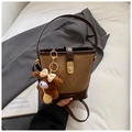 Detail view of brown bucket bag with gold clasp and a cute bear bag charm accessory - Brown with Pendant