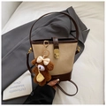 Detail of a beige contrast bucket bag featuring golden rotary lock and puppy charm - Beige With Charm