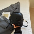 Chic black crossbody bag with gold hardware and embossed logo on grey blazer - Black