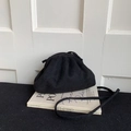 Detail of a black cloud-style clutch bag with matte suede texture on books - Black