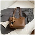 Dettaglio di una borsa tote in pelle marrone con scritte dorate e ciondolo a coniglio - Con Ciondolo / Marrone