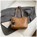Vista dettagliata di una borsa tote in ecopelle marrone con logo oro e ciondolo a coniglio - Con Ciondolo / Marrone