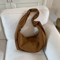 Detail view of the brown suede hobo bag with wide shoulder strap on a white sofa - Brown