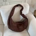 Dark brown suede crescent shoulder bag with knotted strap on a soft beige sofa - Brown