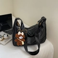 Détail d'un sac hobo noir avec ferrures dorées et un charm ours en peluche sur le côté - Grand / Avec Pendentif / Noir