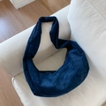 Detail view of deep blue suede crescent bag on white sofa showing fabric texture - Navy Blue